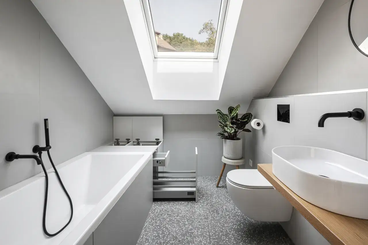 Bagno nel sottotetto con altezza minima, vasca, lavabo, WC e lucernario.