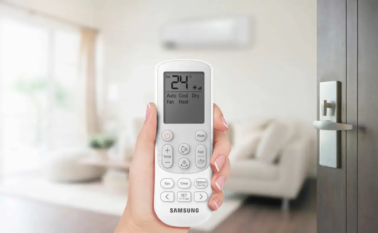 Mano che tiene telecomando per impostare condizionatore aria fredda a 24°C. Modalità Cool selezionata.