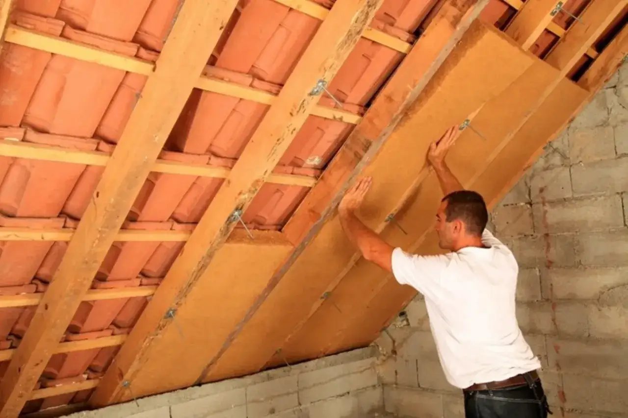 Uomo installa pannelli isolanti per l'isolamento tetto dall'interno fai da te, migliorando l'efficienza energetica.