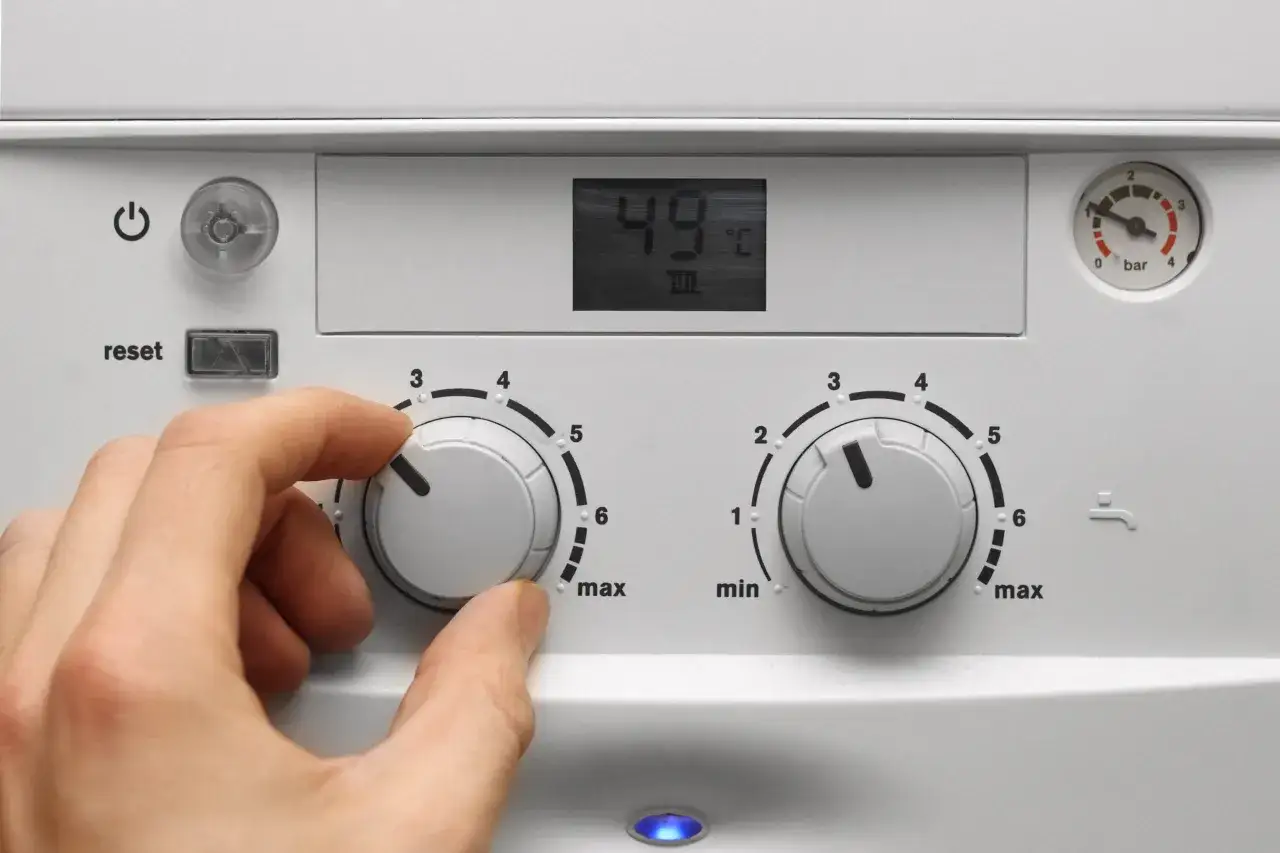 Mano che regola la caldaia spenta senza corrente. Il display mostra 49°C.