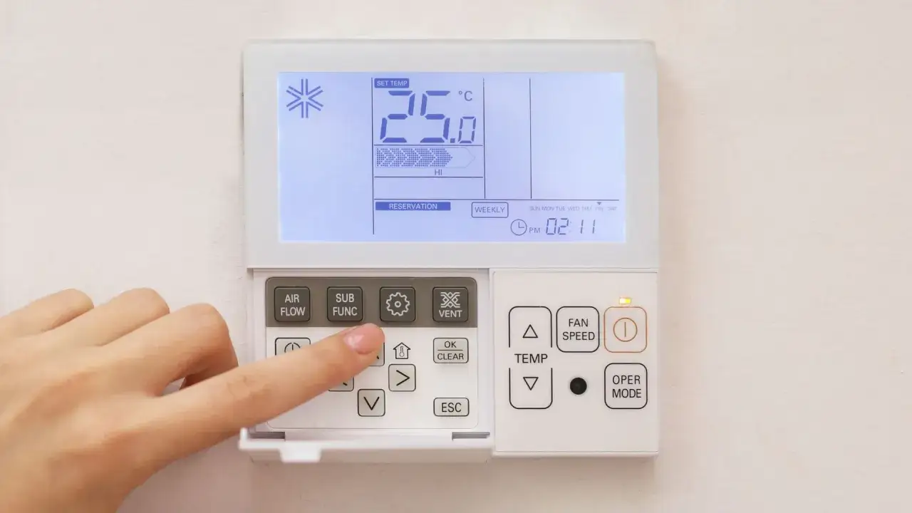Dito si vede un telecomando per condizionatore. La mano preme un tasto, forse per impostare la funzione 