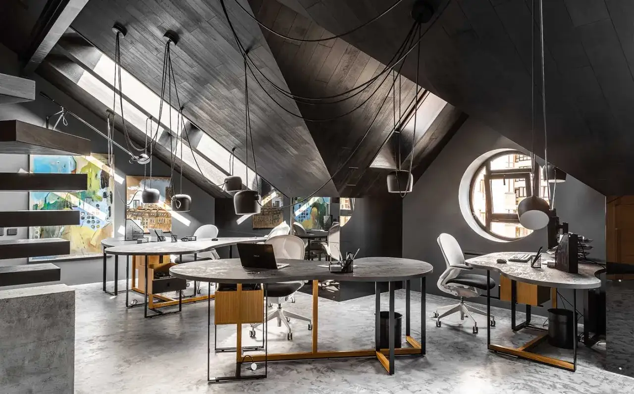 Modern attic office with dark wood ceiling, skylights, and contemporary desks.