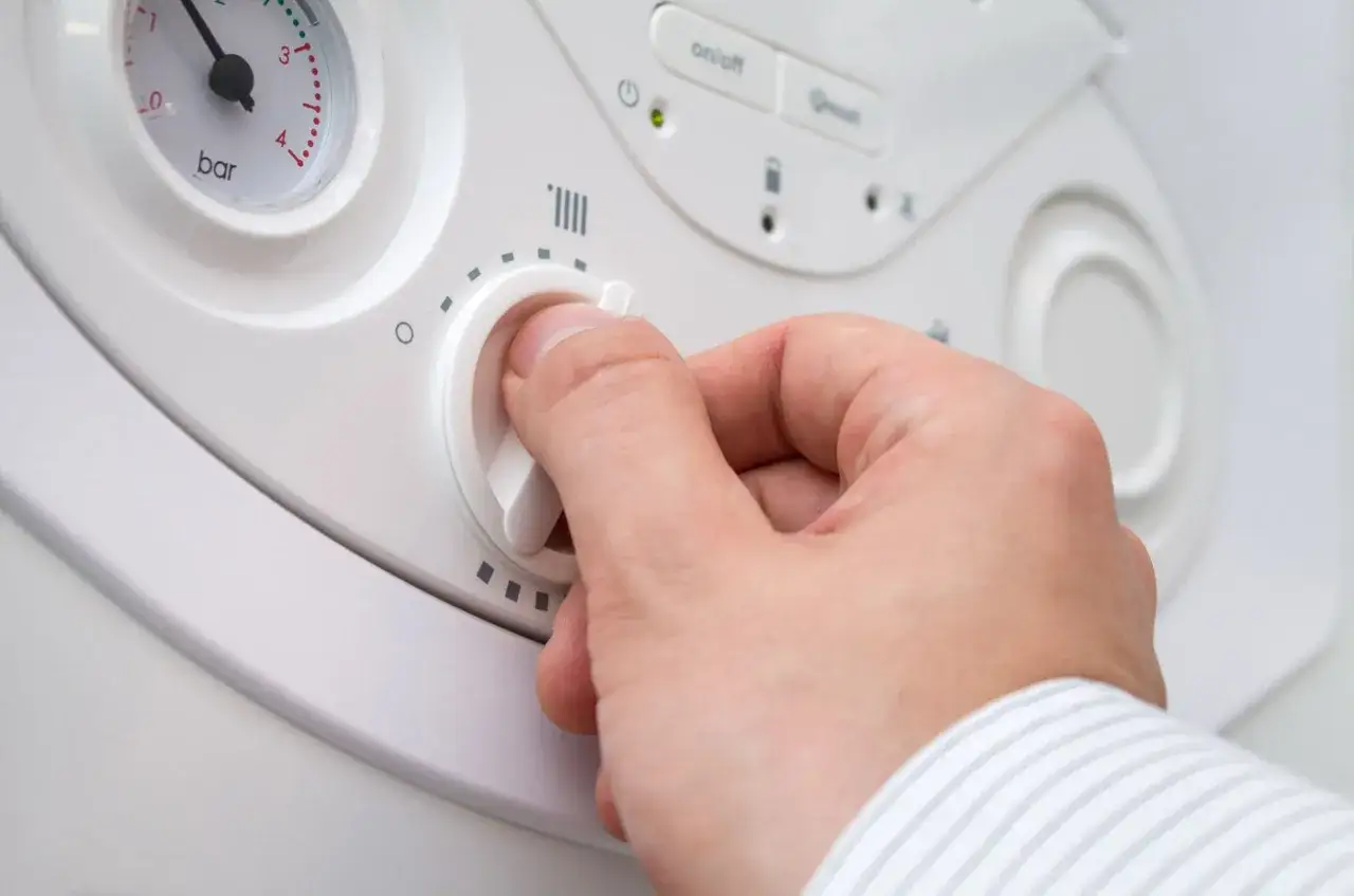 Mano che gira la manopola per alzare la temperatura della caldaia, con indicatore di pressione visibile.