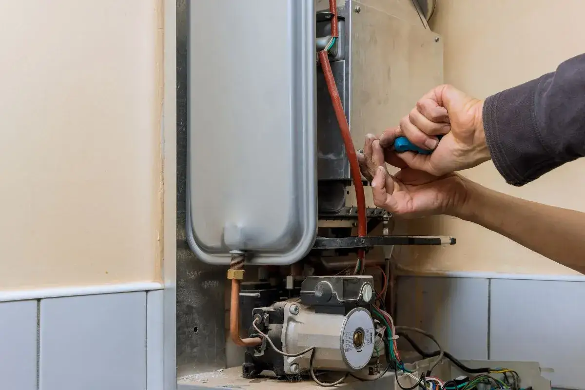 Tecnico ripara uno scaldabagno a gas che sembra pronto a fare il botto.