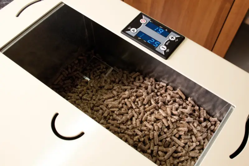 Serbatoio pieno di pellet, alcuni sembrano un po' troppo lunghi per la stufa. Il display digitale mostra 19 e 25.